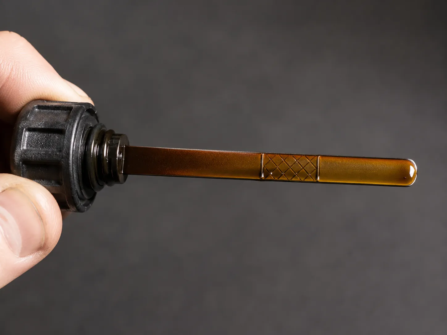 Briggs 725EXi lawn mower dipstick coated with fresh amber oil well above the full mark, showing an overfilled engine oil reading.