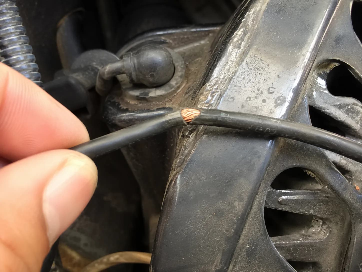 Close-up of a small engine kill wire with worn insulation exposing copper strands where it rubbed against the blower housing, illustrating a common ignition wiring fault.