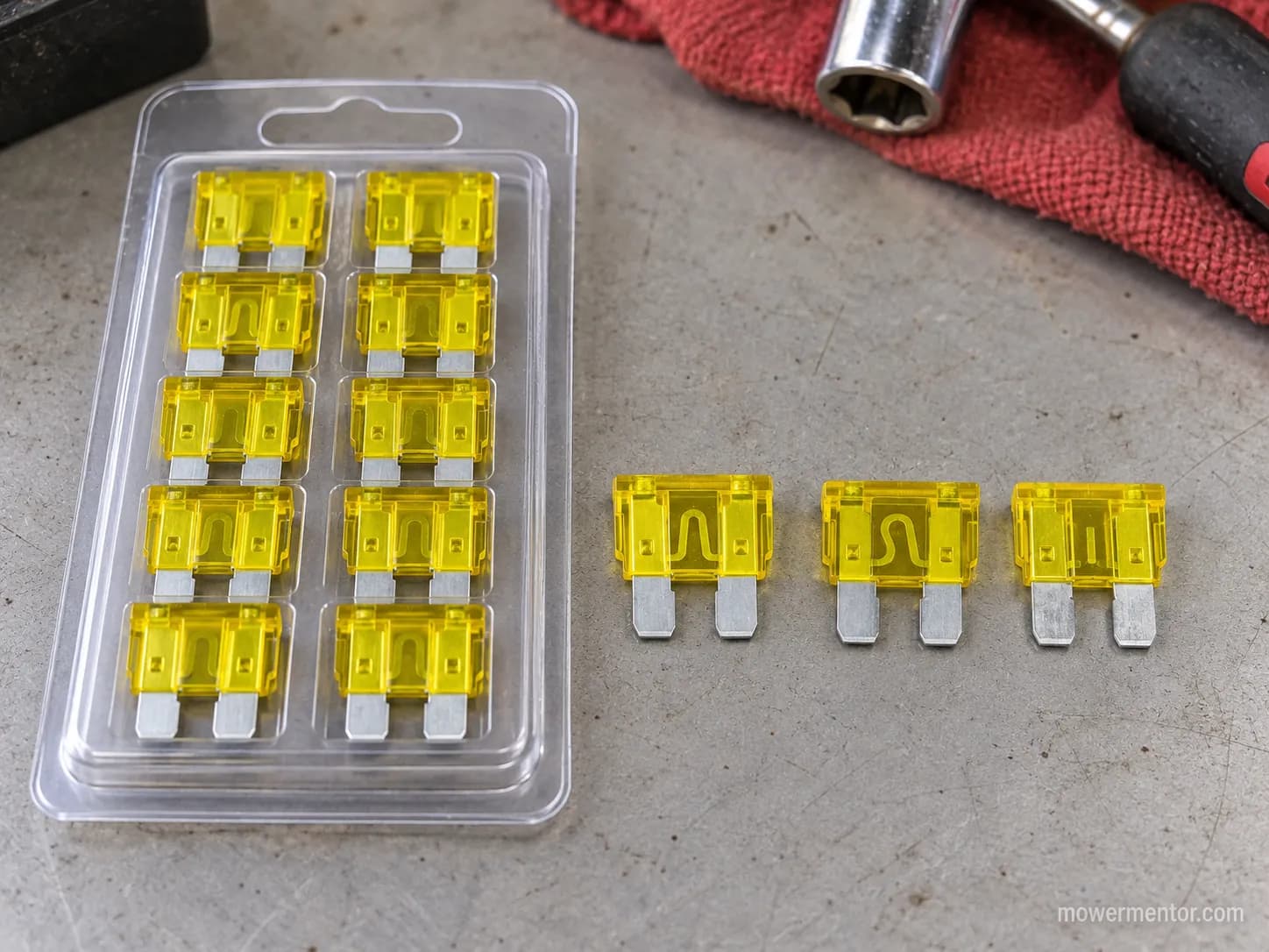 A universal 20 amp blade fuse multipack next to individual OEM riding mower fuses.