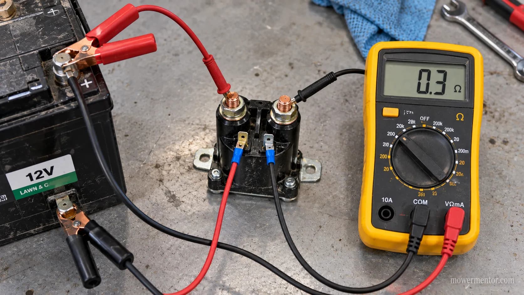 Bench-testing a lawn mower solenoid with jumper wires and a multimeter showing resistance.