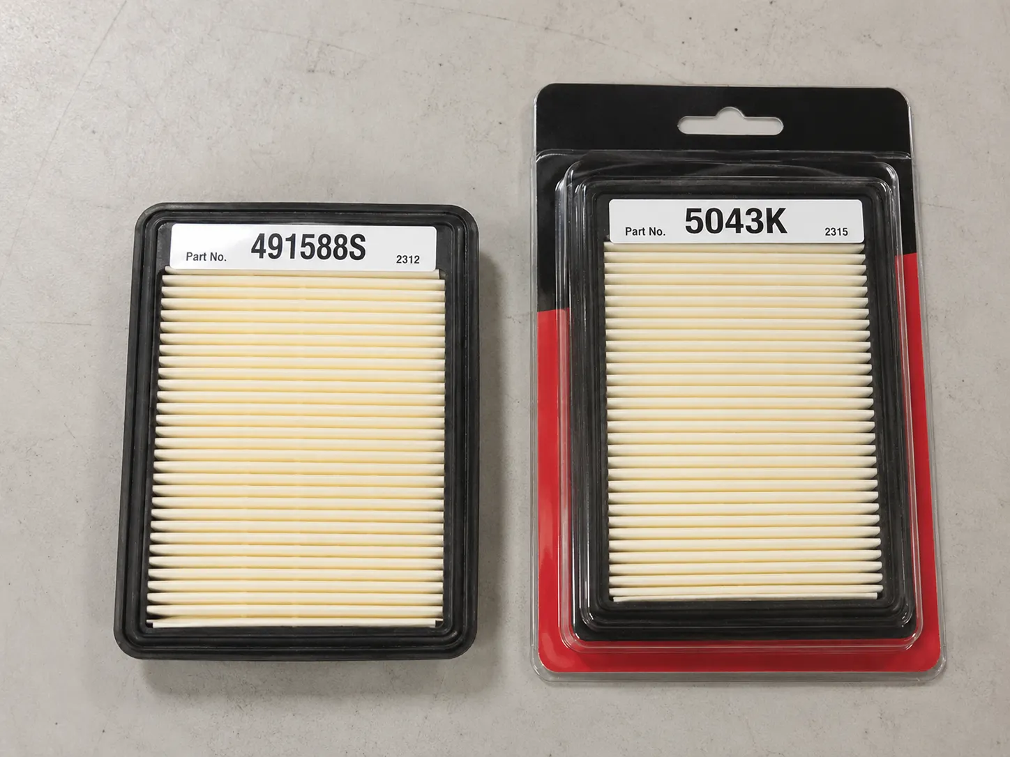 Loose Briggs 491588S pleated air filter beside a sealed 5043K retail package, with both part numbers facing the camera to show they contain the same replacement filter element.