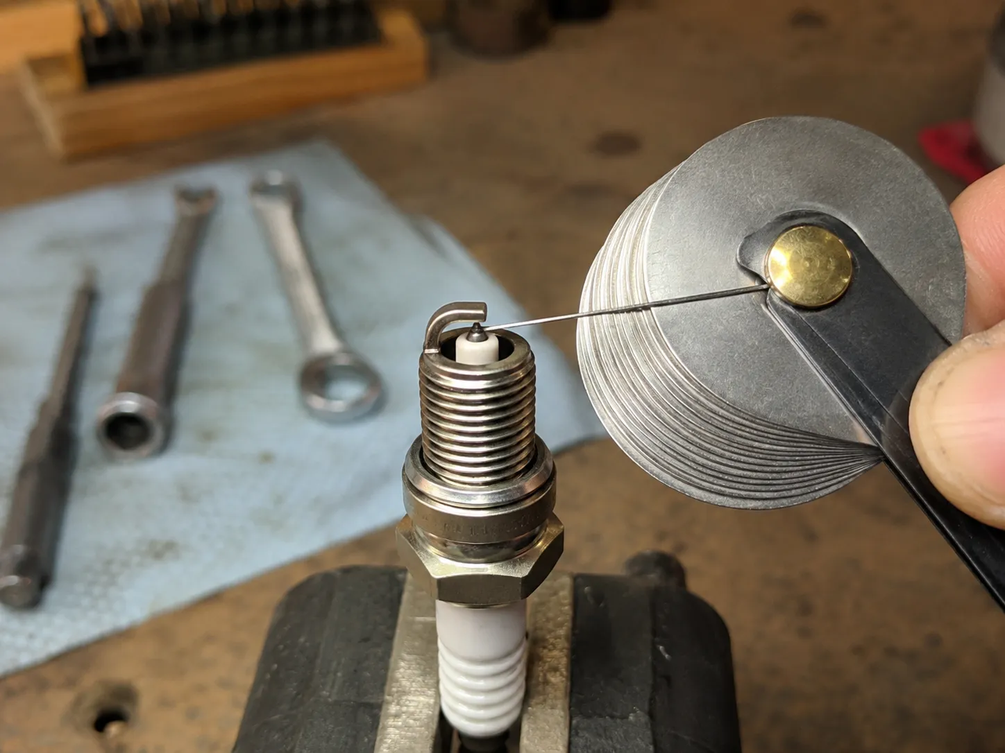 Correcting the gap on a new small engine spark plug using a wire gap gauge, adjusting from 0.026 inch to the recommended 0.030 inch for accurate ignition and reliable engine performance.