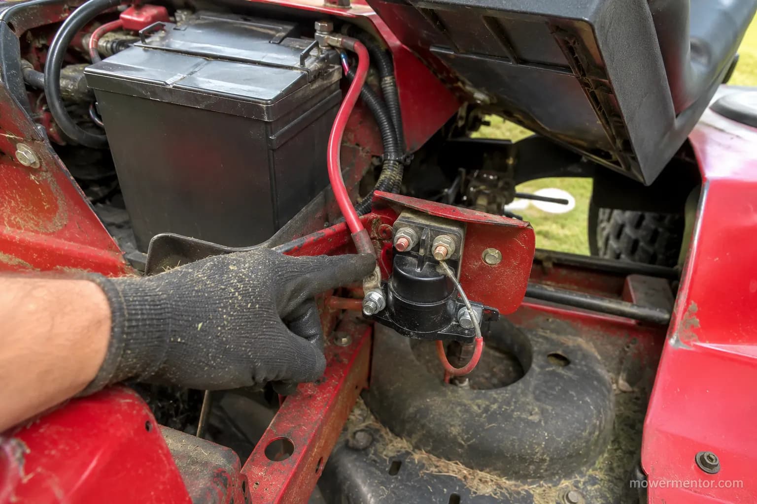 Tracing the battery cable to locate the frame-mounted starter solenoid on a Craftsman riding mower.