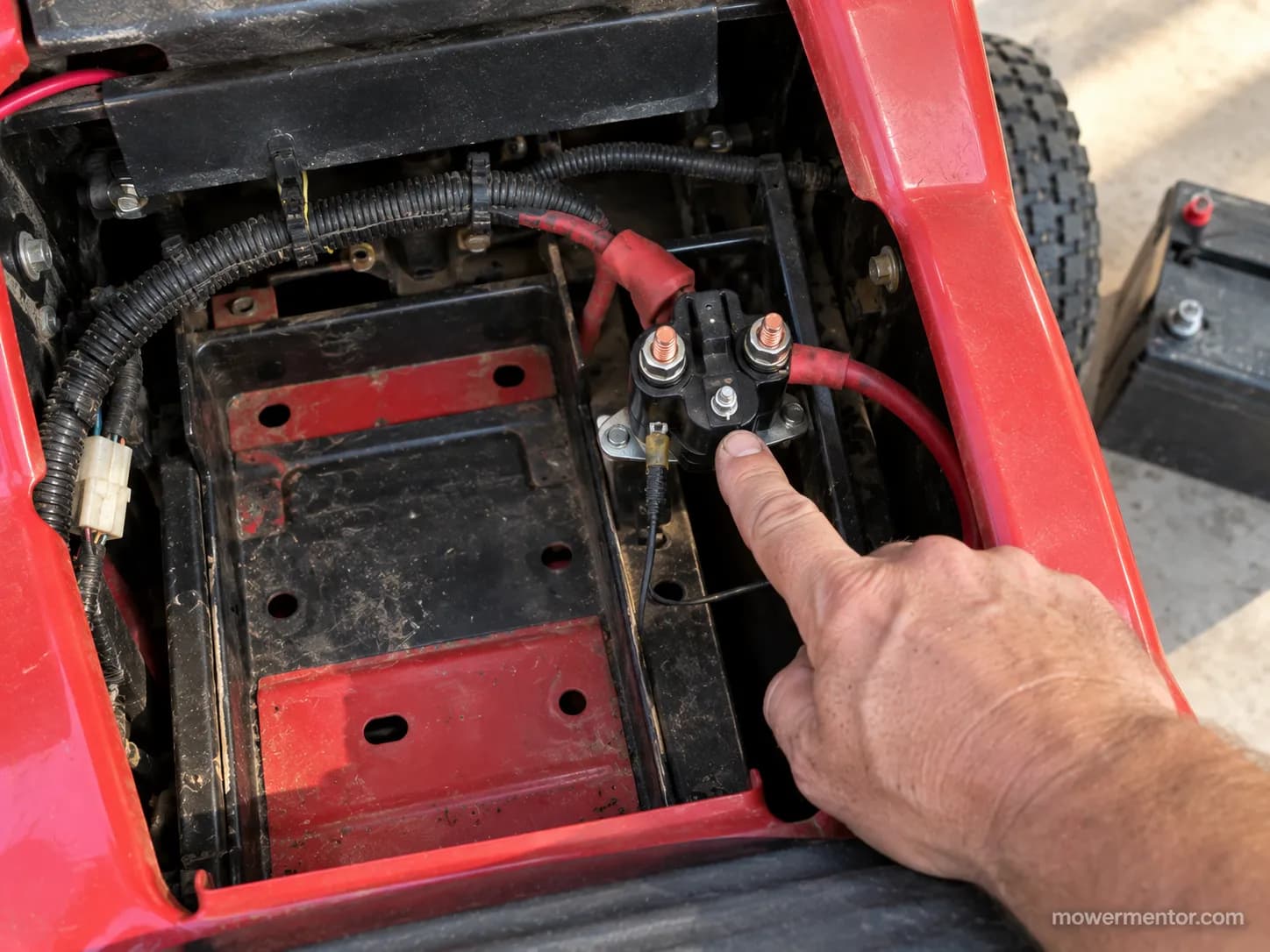 Starter solenoid location under the battery on a Cub Cadet XT1 riding mower.