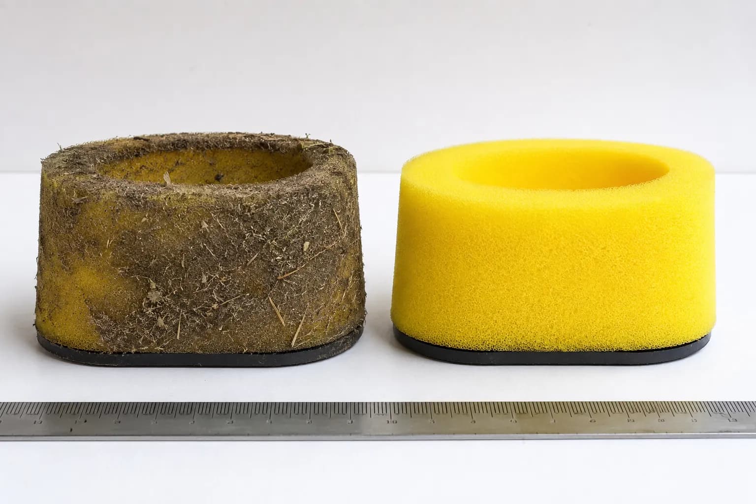 Side-by-side comparison of a dirty and cleaned yellow foam lawn mower air filter with a steel ruler for scale, showing the effect of washing on filter condition and airflow performance.