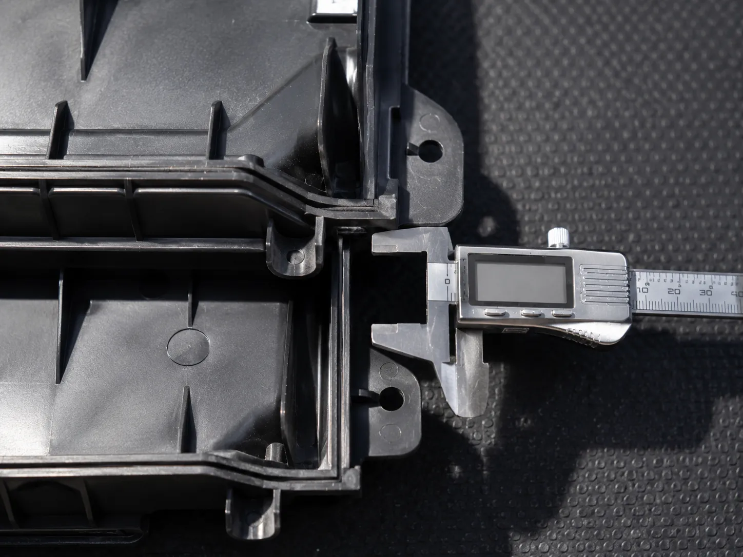Macro comparison of two Honda air cleaner covers overlapped with digital calipers measuring a 6 mm latch offset, highlighting the difference in moulded latch tab alignment.