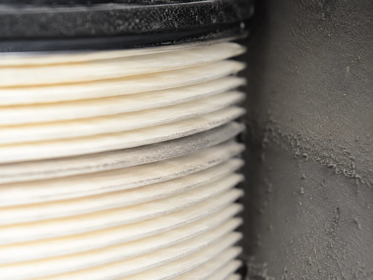 Macro close-up of a John Deere air filter cartridge clean face showing a fine grey dust witness track and lightly dusted housing wall, indicating possible dust bypass or seal leakage.