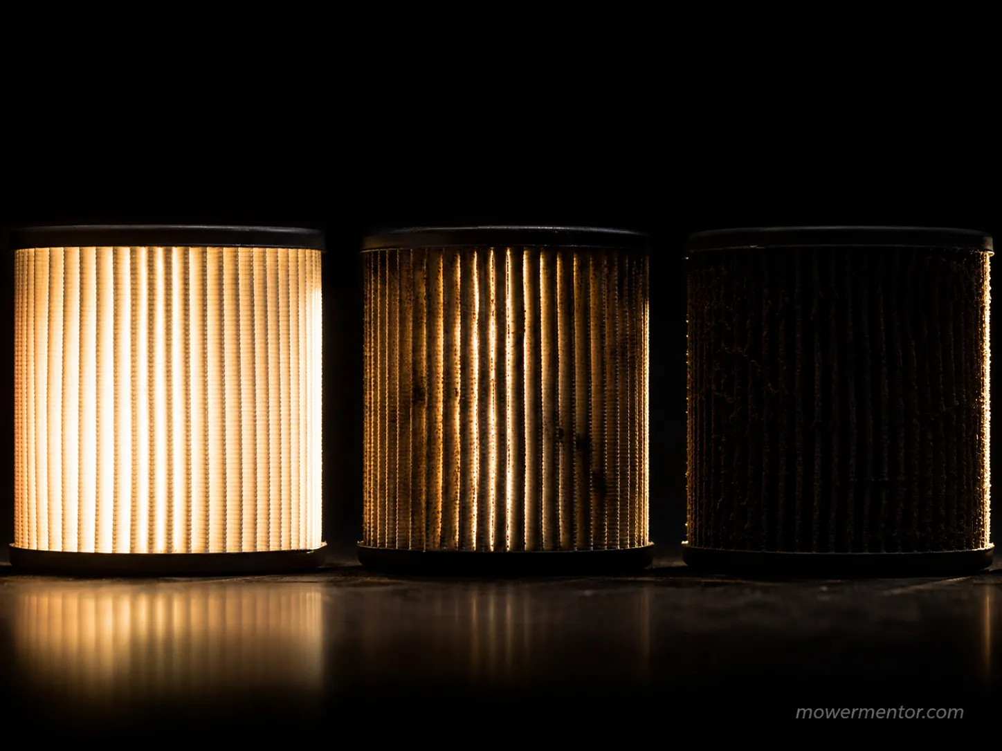 Three lawn mower air filters backlit to show light transmission at different dirt loadings, from bright and clean to nearly opaque.