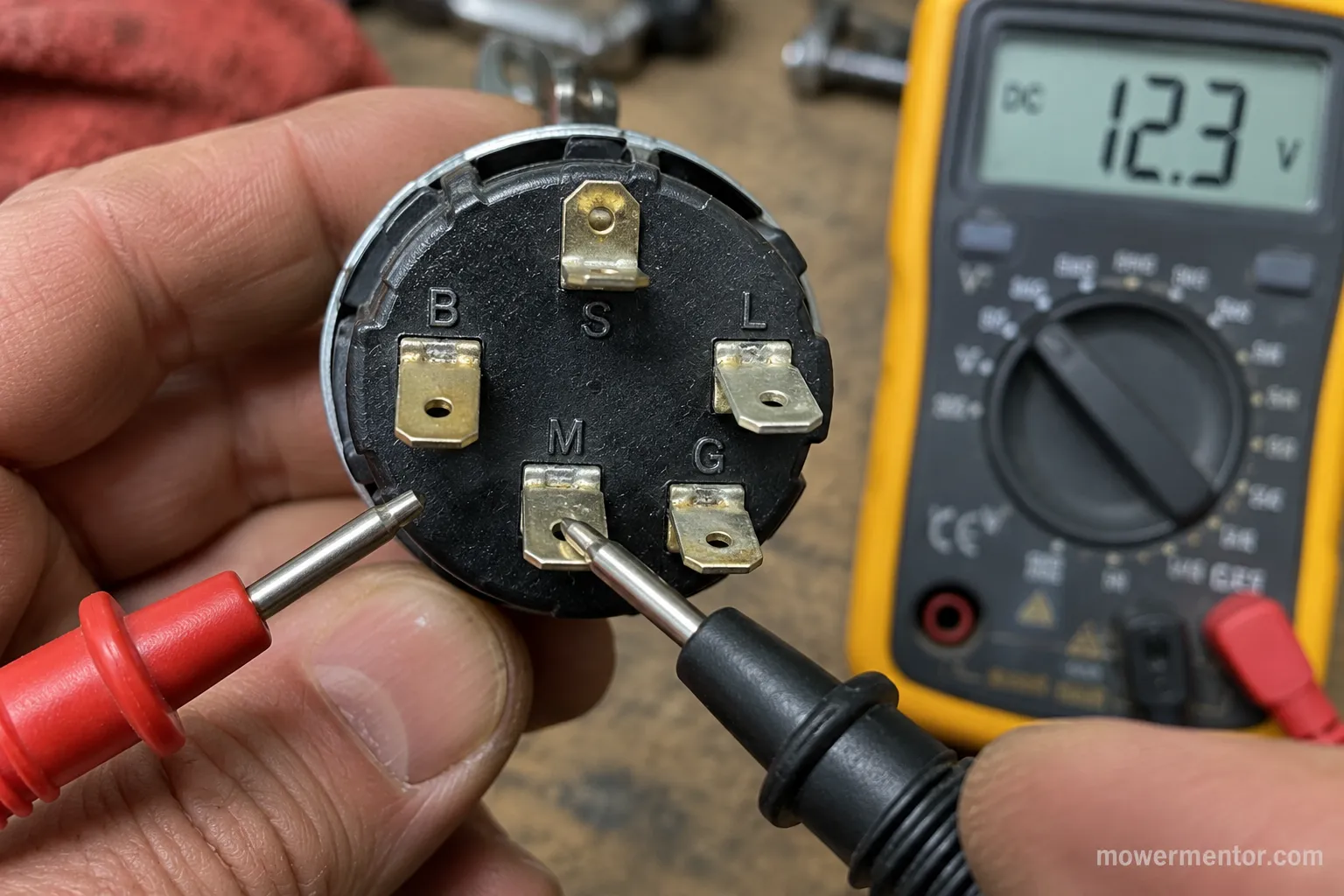 Back of a five-post lawn mower ignition switch with a multimeter probe on the M terminal during a continuity test.