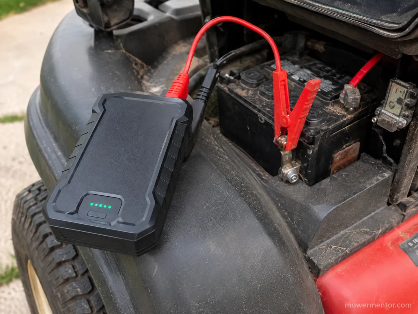 A 12-volt lithium jump pack connected to a riding mower battery during a jump start.