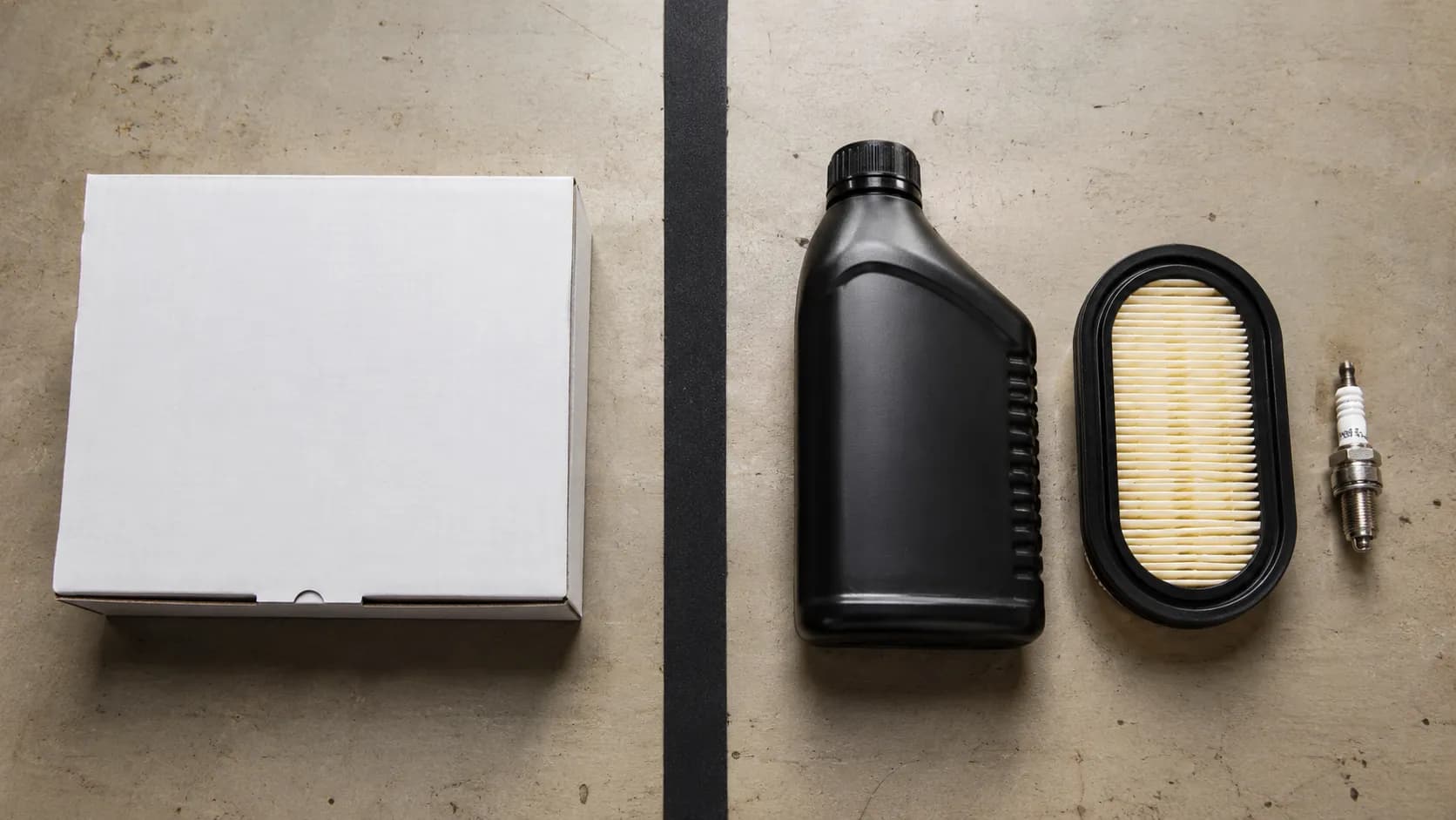 OEM maintenance kit box beside separately purchased oil, air filter, and spark plug on a workbench, shown side by side for an easy maintenance parts comparison.