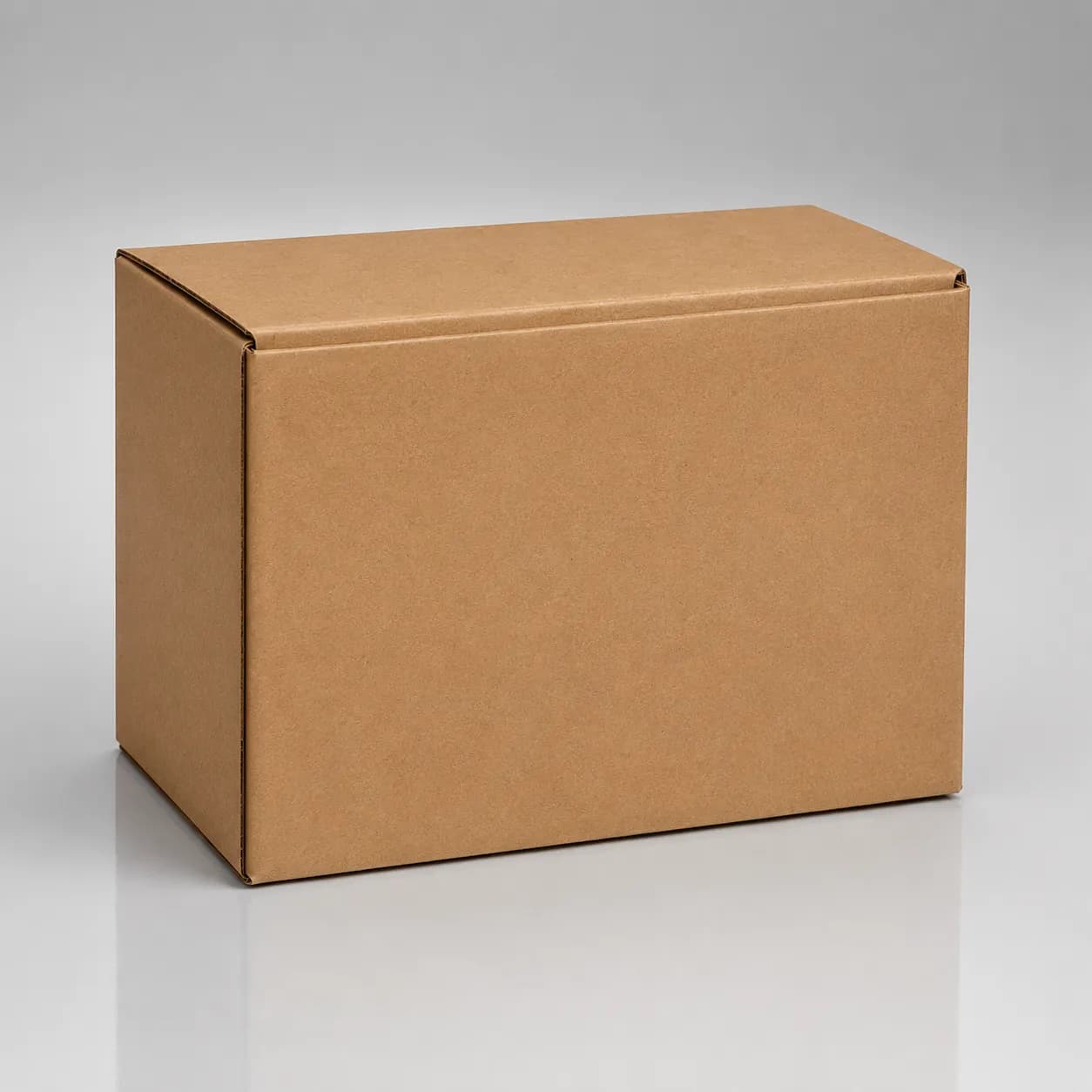 Plain rectangular cardboard parts box photographed in a studio on a light gray seamless background with soft lighting, subtle floor reflection, and no branding or printed graphics.