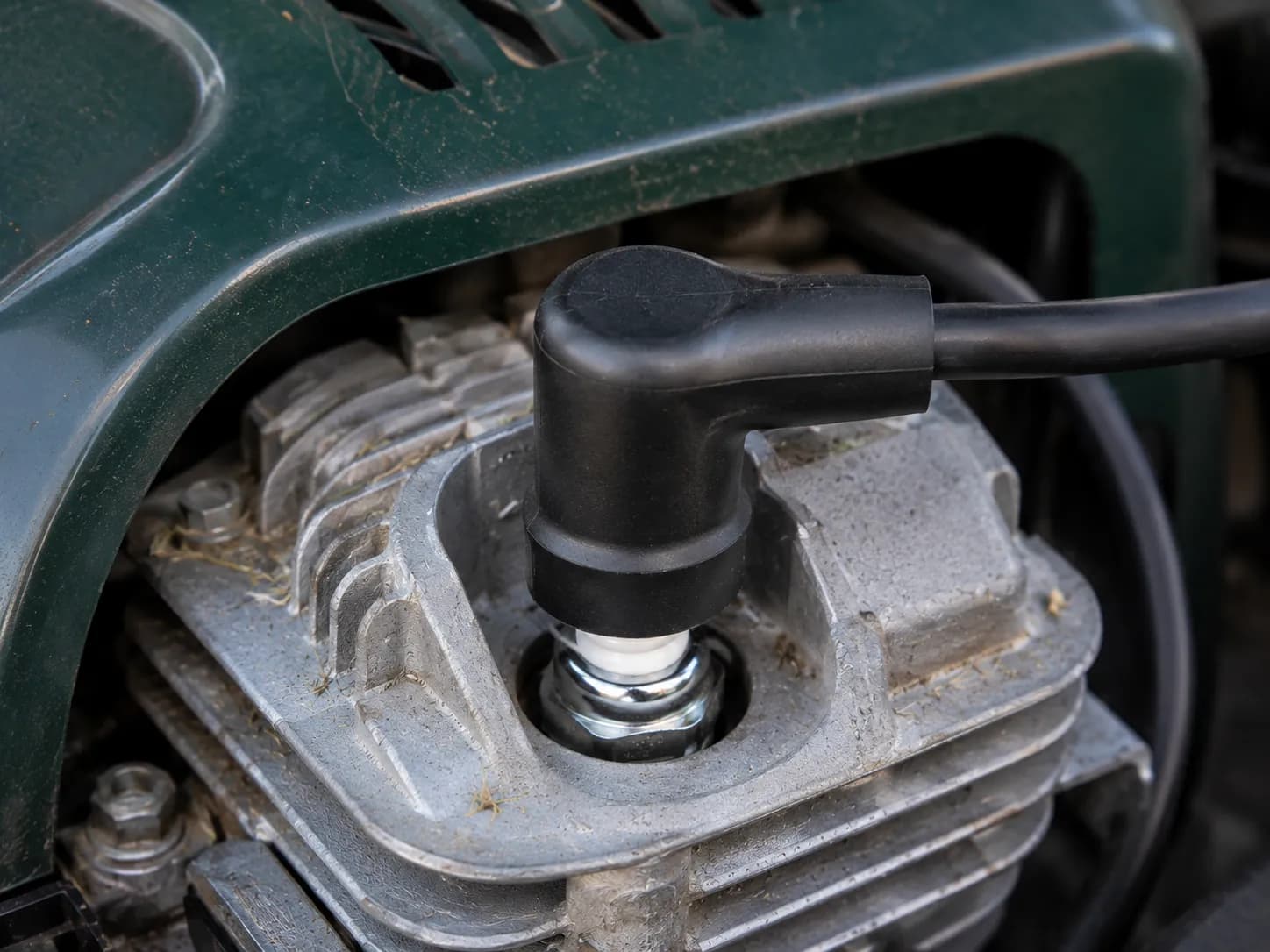 Spark plug boot pressed squarely onto the terminal of a newly installed lawn mower spark plug, showing the correct seating of the ignition lead on the engine cylinder head.