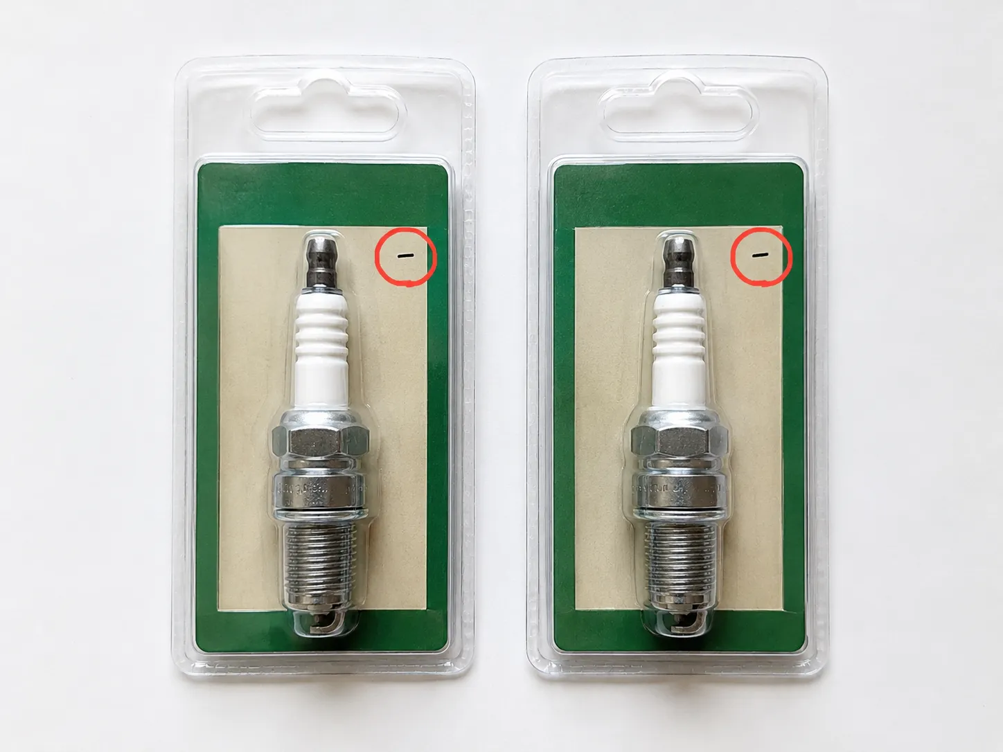 Overhead comparison of two nearly identical packaged spark plugs with red circles highlighting a small label difference, illustrating how a single character can distinguish similar parts.