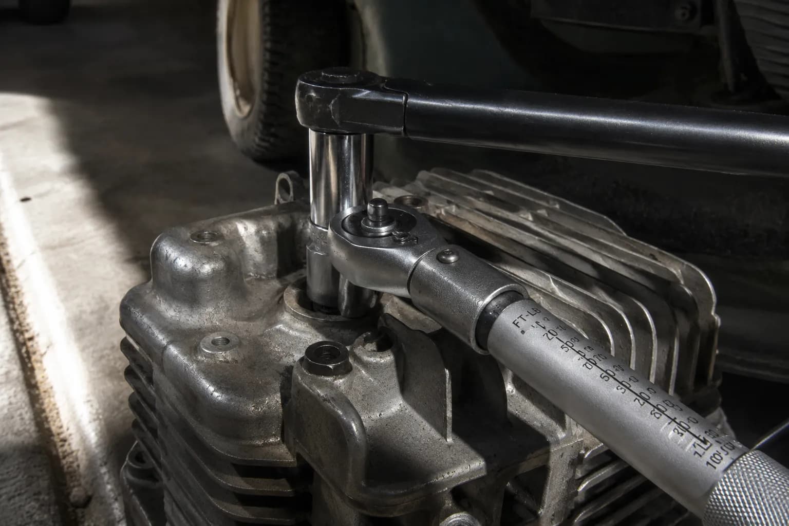 Torque wrench set to 57 ft-lb with a six-point spark plug socket and breaker bar on a seized spark plug in an aluminum cylinder head before the plug breaks free.