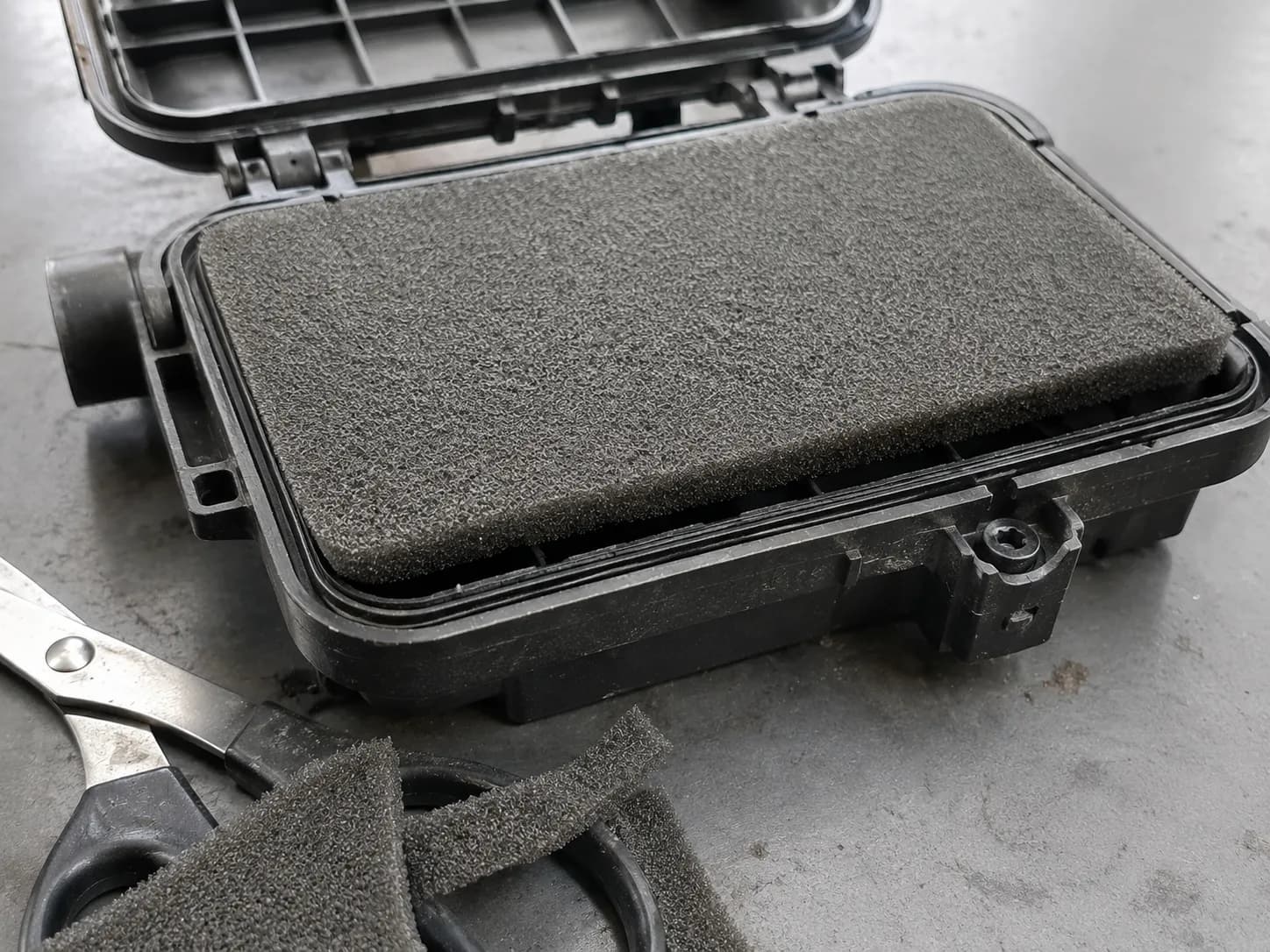 Cut universal foam air filter sheet sitting above a rigid panel housing edge, leaving a visible gap that could allow unfiltered air to bypass the filter.